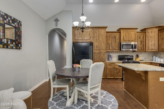 kitchen featuring dark wood finished floors, lofted ceiling, brown cabinetry, a notable chandelier, and black appliances