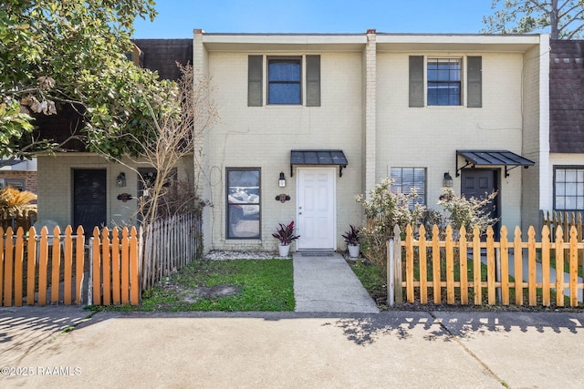 townhome / multi-family property with a fenced front yard and brick siding