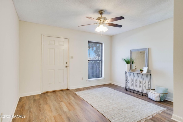 foyer entrance featuring baseboards, a textured ceiling, ceiling fan, and wood finished floors