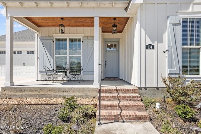 property entrance with board and batten siding, a porch, and an attached garage