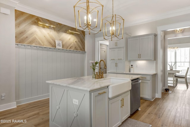 kitchen with light wood finished floors, ornamental molding, a sink, pendant lighting, and stainless steel dishwasher