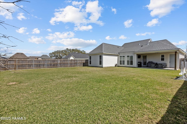 rear view of property with a patio area, a yard, a fenced backyard, and a shingled roof