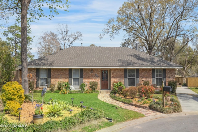 ranch-style home featuring brick siding, roof with shingles, a front yard, and fence