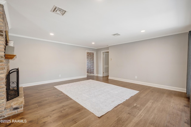 unfurnished living room featuring wood finished floors, visible vents, baseboards, a fireplace, and ornamental molding