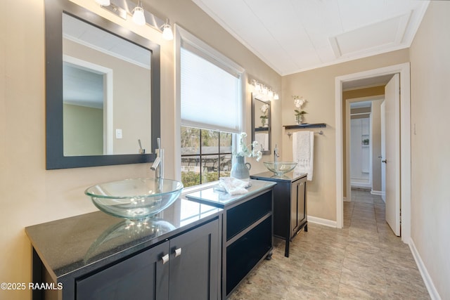 bathroom with two vanities, ornamental molding, baseboards, and a sink