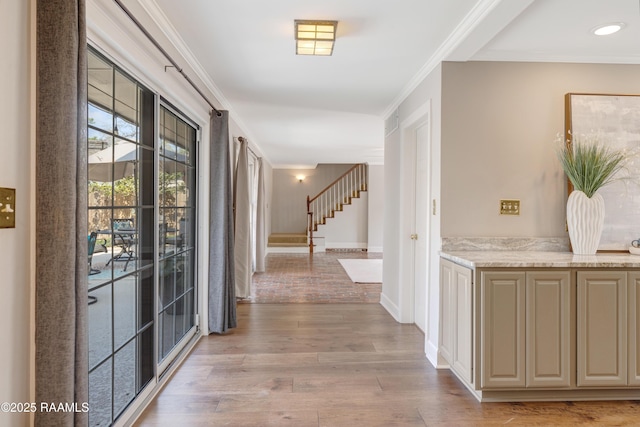 corridor featuring stairs, baseboards, crown molding, and light wood finished floors