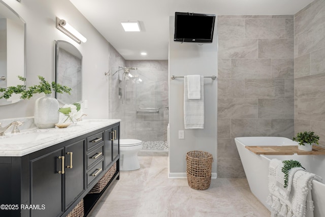 bathroom featuring double vanity, a freestanding bath, a stall shower, and a sink