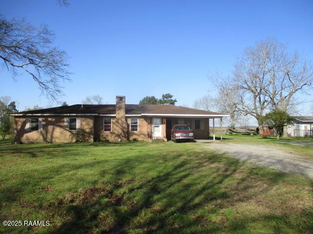 view of front of property featuring dirt driveway, a chimney, and a front lawn