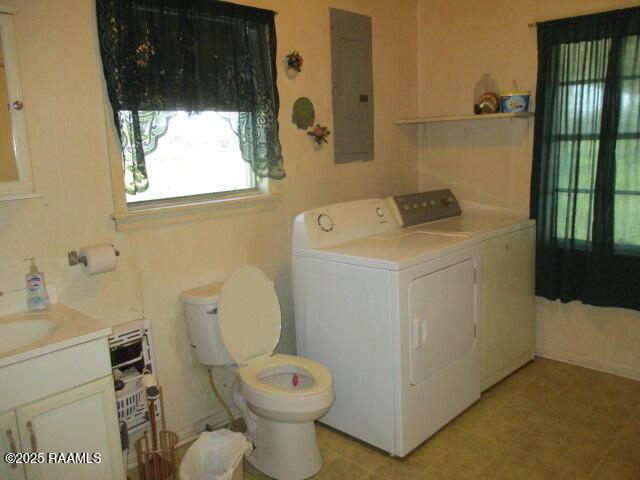 clothes washing area with electric panel, separate washer and dryer, laundry area, and a sink