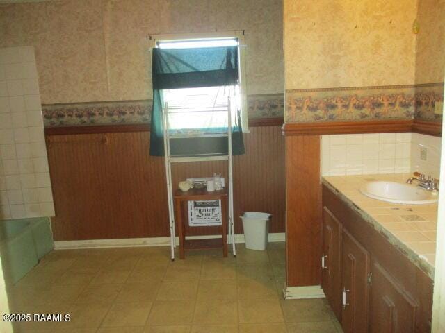 full bath featuring wallpapered walls, vanity, and a wainscoted wall