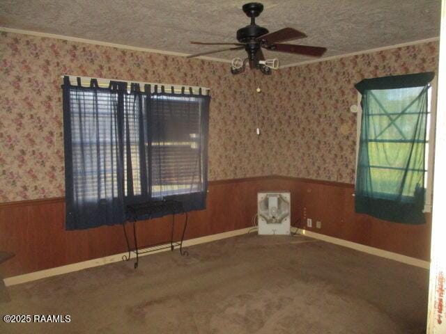 carpeted spare room with wainscoting, a textured ceiling, and wallpapered walls