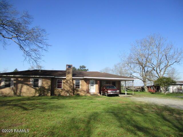 view of front of property with driveway, a chimney, a front lawn, a carport, and brick siding