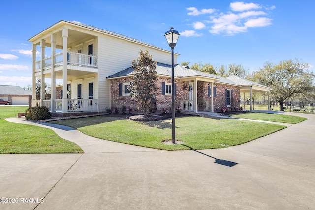 view of front facade with a balcony, covered porch, concrete driveway, a front yard, and brick siding