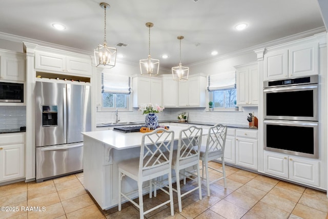 kitchen featuring a kitchen breakfast bar, ornamental molding, appliances with stainless steel finishes, and a chandelier