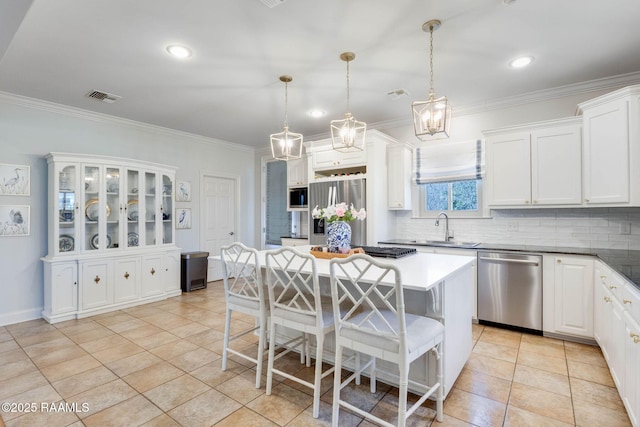 kitchen with a kitchen bar, visible vents, a sink, tasteful backsplash, and stainless steel appliances