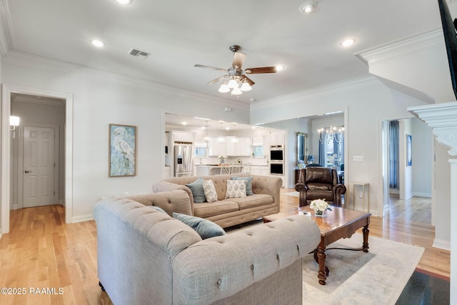 living room featuring visible vents, crown molding, baseboards, ceiling fan, and light wood-style floors