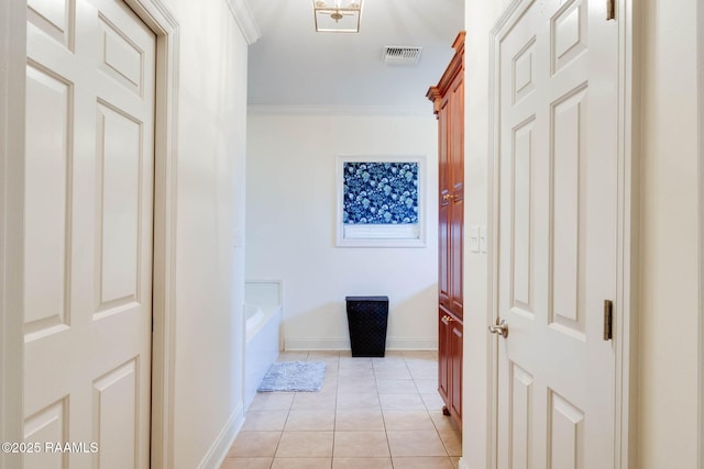 hallway featuring visible vents, baseboards, light tile patterned flooring, and crown molding