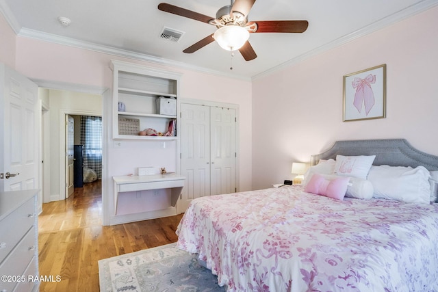 bedroom with crown molding, a closet, visible vents, and light wood finished floors