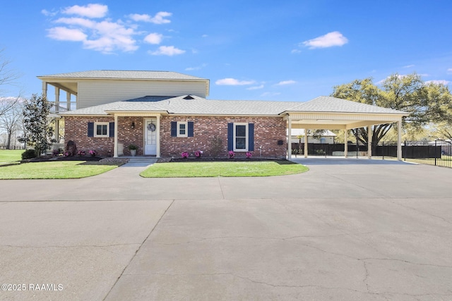 view of front of home with brick siding, concrete driveway, a front lawn, and fence