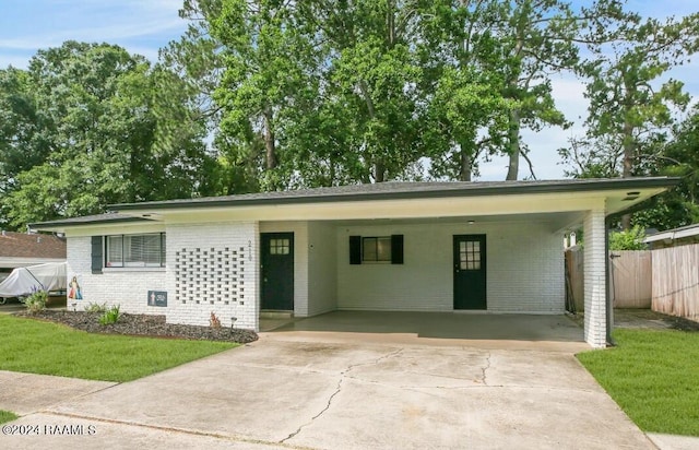 single story home with driveway, fence, a front yard, a carport, and brick siding