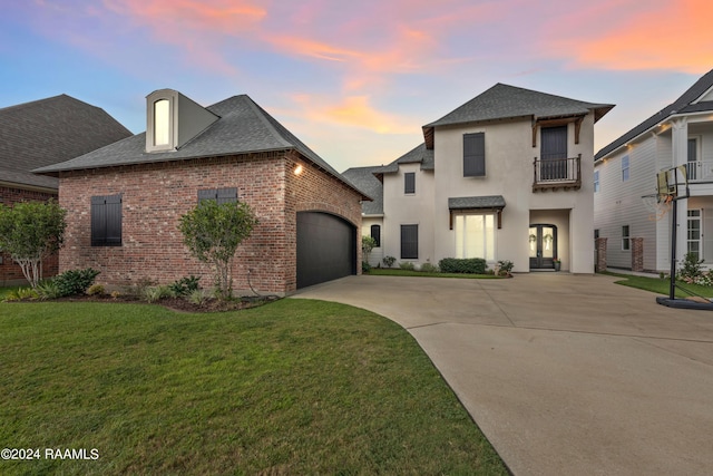 view of front of home featuring a lawn, a balcony, concrete driveway, an attached garage, and brick siding