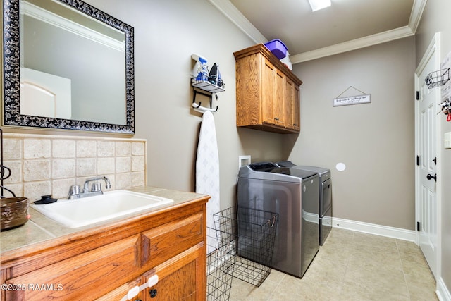 laundry area with crown molding, baseboards, washer and clothes dryer, cabinet space, and a sink