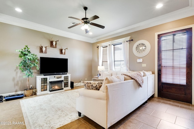 living room featuring a glass covered fireplace, plenty of natural light, ornamental molding, and a ceiling fan