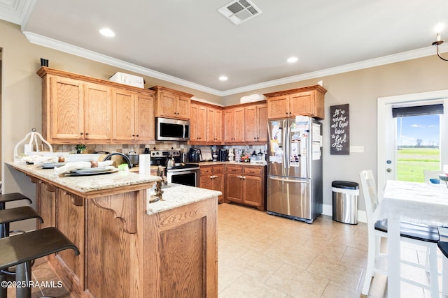 kitchen featuring a peninsula, ornamental molding, visible vents, and stainless steel appliances