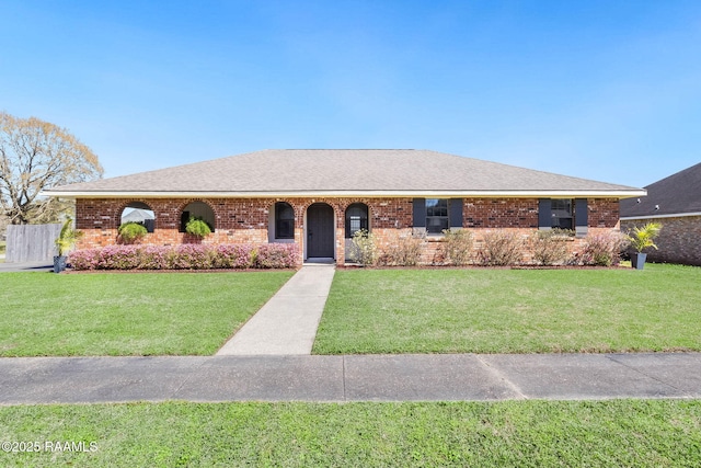 ranch-style home with brick siding, a shingled roof, and a front yard