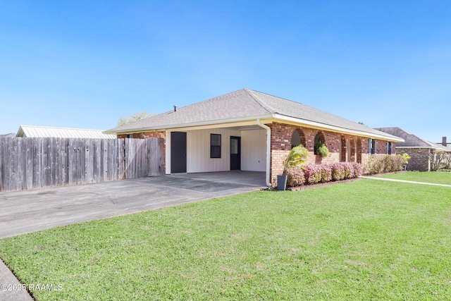 view of front of property featuring brick siding, fence, a front yard, a carport, and driveway