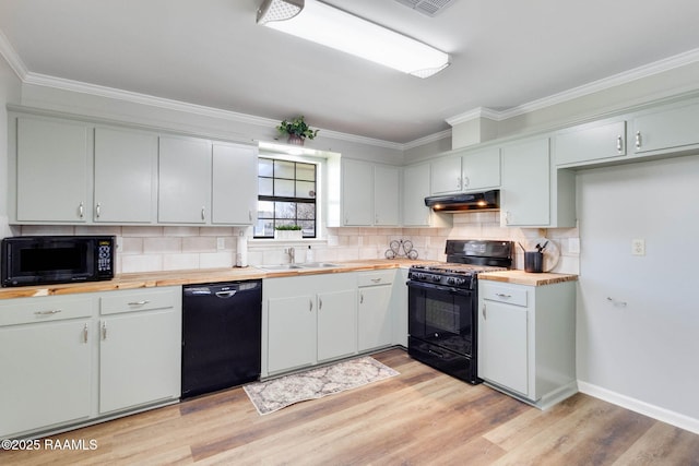 kitchen featuring wooden counters, crown molding, under cabinet range hood, black appliances, and a sink