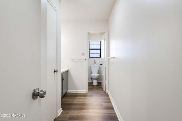 bathroom featuring baseboards, toilet, wood finished floors, and vanity