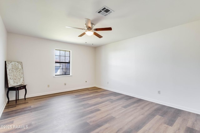 spare room with ceiling fan, wood finished floors, visible vents, and baseboards