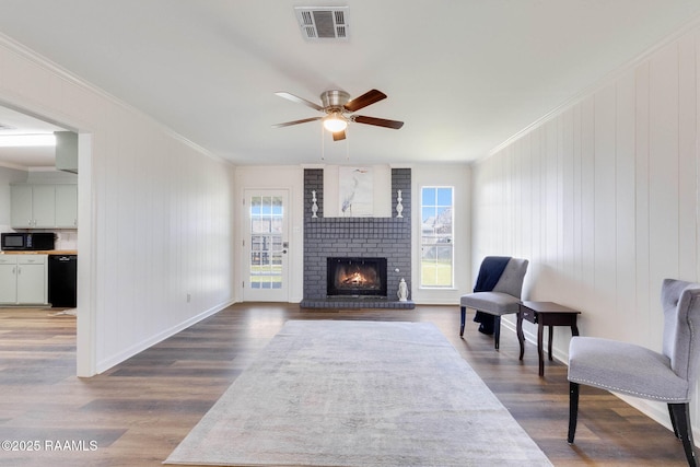 living area with a wealth of natural light, visible vents, and ornamental molding