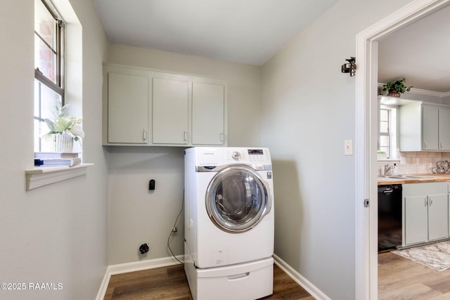 washroom featuring washer / dryer, plenty of natural light, cabinet space, and light wood finished floors