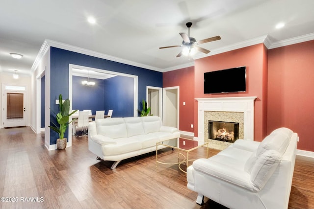 living area with a high end fireplace, ornamental molding, baseboards, and wood finished floors