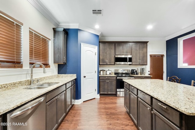 kitchen with visible vents, dark brown cabinets, crown molding, appliances with stainless steel finishes, and a sink