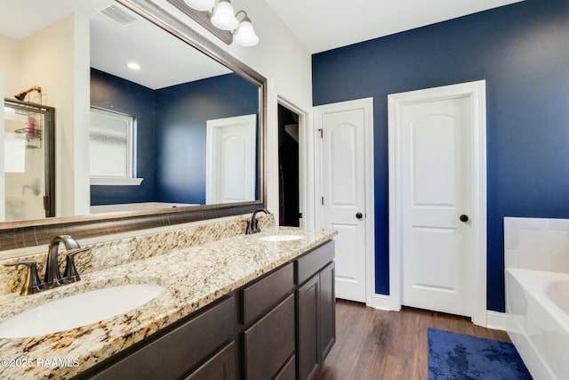 full bathroom featuring visible vents, wood finished floors, a garden tub, and a sink