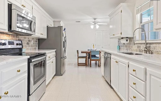 kitchen with white cabinets, appliances with stainless steel finishes, a ceiling fan, and a sink