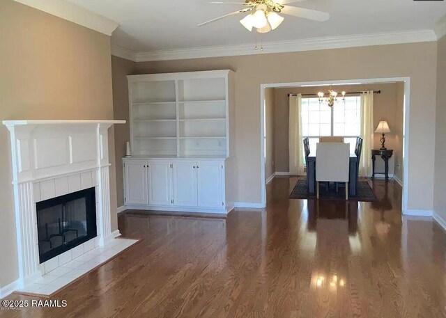 unfurnished living room featuring a fireplace, crown molding, baseboards, and wood finished floors