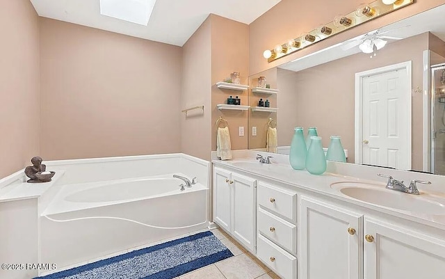 full bathroom with double vanity, a skylight, a sink, tile patterned flooring, and a bath