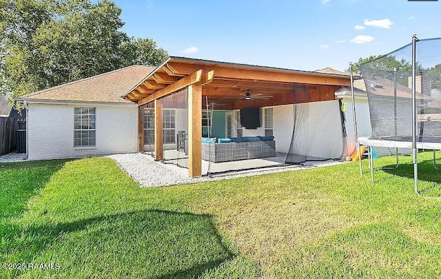 back of house with outdoor lounge area, a patio, a trampoline, and a lawn