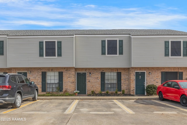 multi unit property featuring uncovered parking, brick siding, and a shingled roof