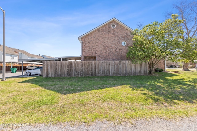 view of home's exterior with brick siding, a yard, and fence