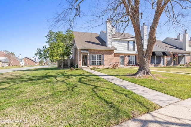 view of front of home with a front lawn, brick siding, and roof with shingles