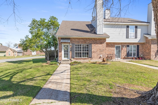 view of front facade featuring a front yard, brick siding, and a chimney