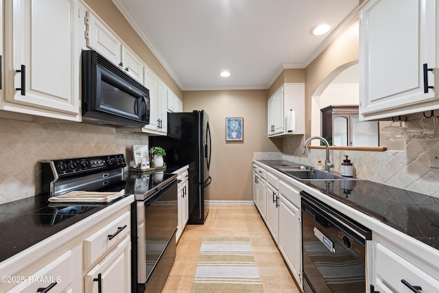 kitchen with black appliances, a sink, dark countertops, white cabinetry, and crown molding