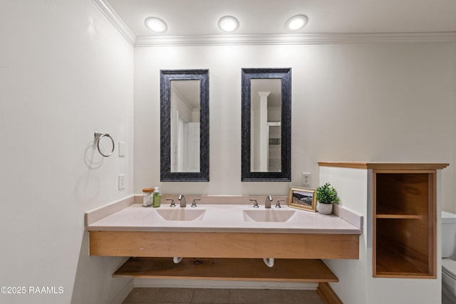 bathroom with double vanity, toilet, crown molding, and a sink