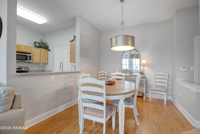 dining space featuring light wood-style floors and baseboards