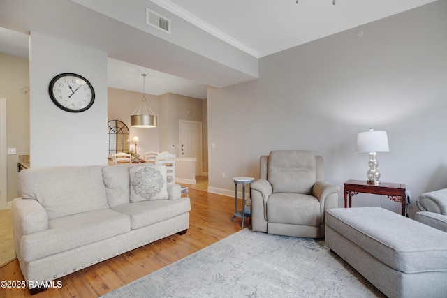 living area with visible vents, ornamental molding, baseboards, and wood finished floors